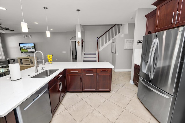 kitchen featuring open floor plan, stainless steel appliances, light countertops, a sink, and light tile patterned flooring