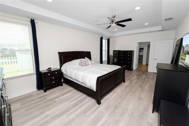 bedroom featuring recessed lighting, visible vents, baseboards, light wood finished floors, and a raised ceiling