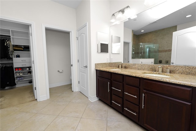 full bath with double vanity, walk in shower, a sink, and tile patterned floors