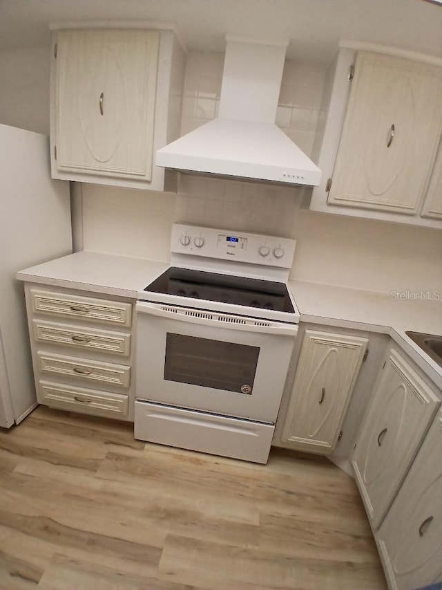 11200 102nd Ave Unit 125, Seminole, FL 33778 - kitchen featuring range hood, light wood finished floors, light countertops, tasteful backsplash, and white range with electric stovetop