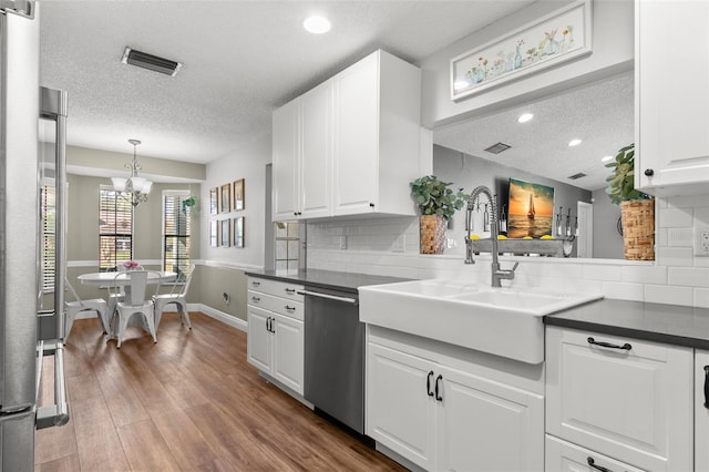 kitchen with tasteful backsplash, white cabinetry, dark hardwood / wood-style flooring, stainless steel dishwasher, and a notable chandelier