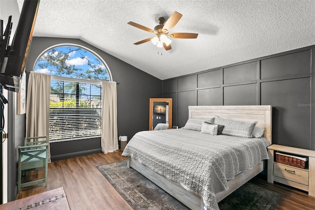 bedroom with dark hardwood / wood-style flooring, ceiling fan, lofted ceiling, and a textured ceiling