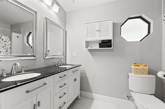 bathroom with vanity, toilet, curtained shower, and a textured ceiling