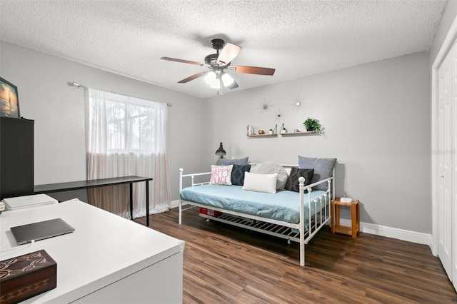 bedroom with dark hardwood / wood-style flooring, ceiling fan, a closet, and a textured ceiling