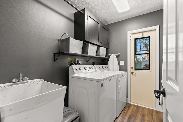 washroom with sink, cabinets, a textured ceiling, washing machine and clothes dryer, and dark hardwood / wood-style flooring