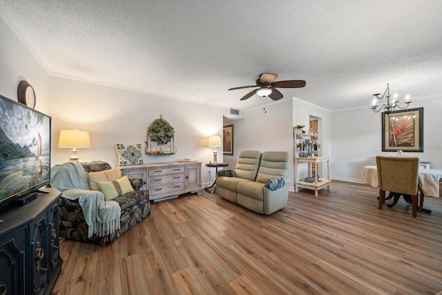 living room with ceiling fan with notable chandelier, wood-type flooring, ornamental molding, and a textured ceiling