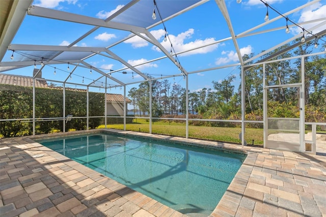 view of pool with a patio, a yard, and glass enclosure