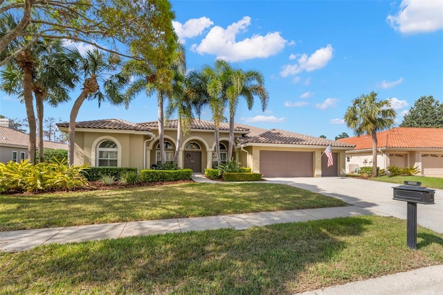 mediterranean / spanish home with a garage and a front lawn