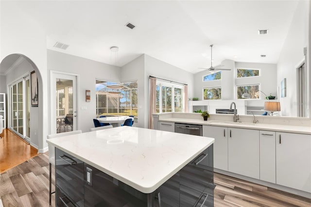 kitchen with sink, a center island, light wood-type flooring, dishwasher, and white cabinets