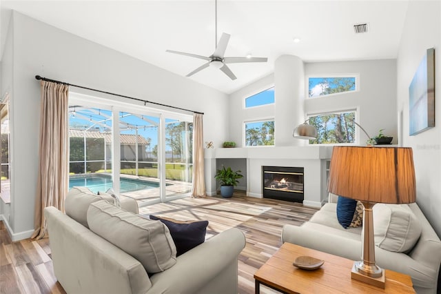 living room with ceiling fan, high vaulted ceiling, and light hardwood / wood-style flooring