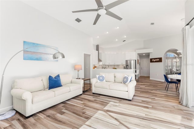 living room featuring ceiling fan, lofted ceiling, and light hardwood / wood-style flooring