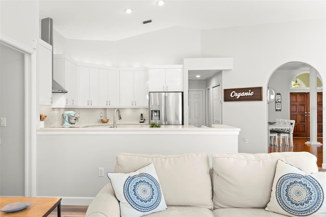 kitchen featuring sink, tasteful backsplash, vaulted ceiling, stainless steel fridge with ice dispenser, and white cabinets