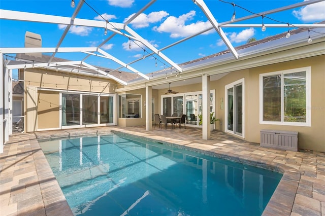 view of swimming pool with ceiling fan, glass enclosure, and a patio area