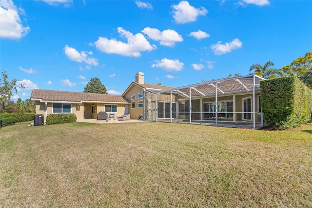 back of property featuring a yard, a patio area, and glass enclosure