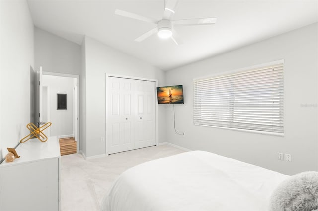 bedroom featuring ceiling fan, a closet, lofted ceiling, and light carpet