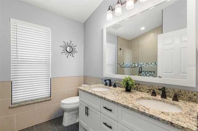 bathroom with tile walls, vanity, a shower with shower door, tile patterned floors, and toilet