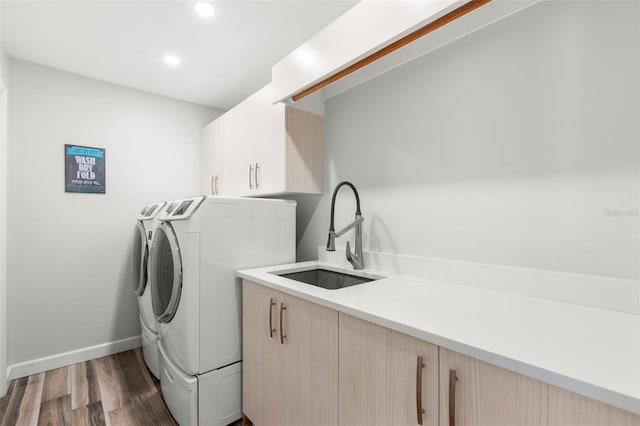 clothes washing area with dark wood-type flooring, cabinets, sink, and washing machine and dryer