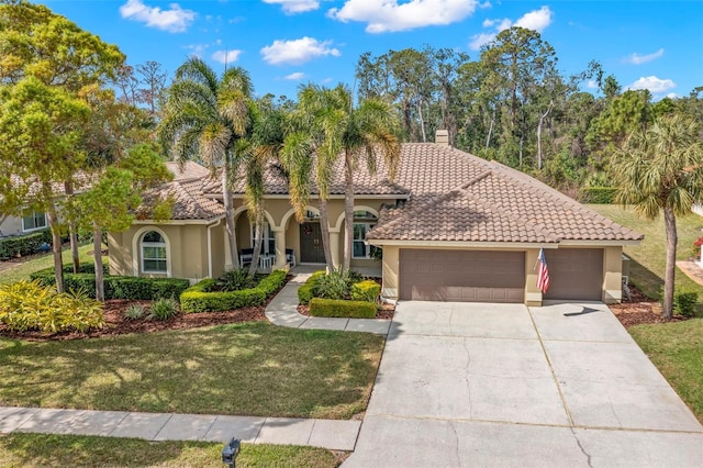 mediterranean / spanish-style house featuring a garage and a front yard