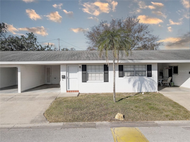 single story home featuring a carport and a lawn