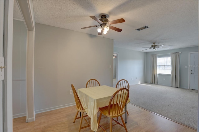 dining space with ceiling fan, a textured ceiling, and light hardwood / wood-style flooring