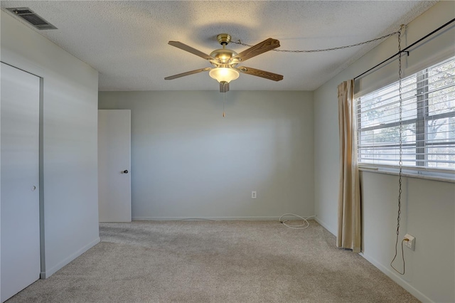 unfurnished bedroom featuring ceiling fan, light carpet, and a textured ceiling