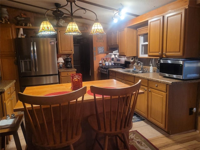 kitchen with stainless steel appliances, sink, pendant lighting, and light stone counters