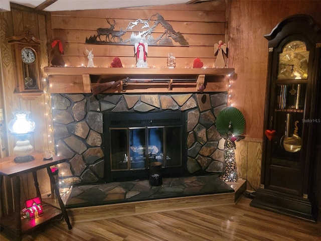 details with hardwood / wood-style flooring, a stone fireplace, and wooden walls