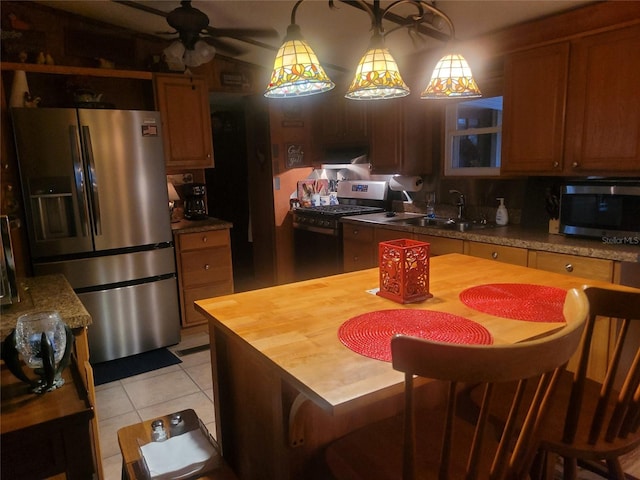 kitchen featuring decorative light fixtures, sink, light tile patterned floors, ceiling fan, and stainless steel appliances