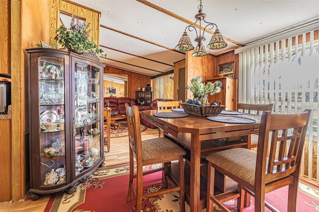 dining area featuring hardwood / wood-style flooring, a textured ceiling, and wood walls