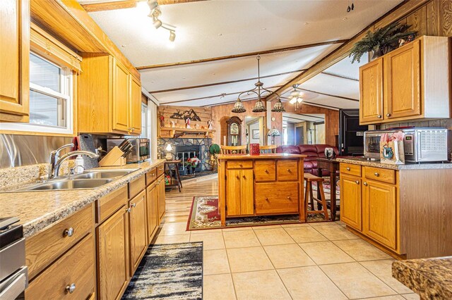 kitchen featuring a fireplace, sink, vaulted ceiling with beams, range, and light tile patterned floors