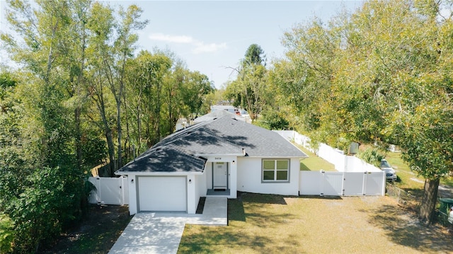 view of front of house with concrete driveway, an attached garage, a gate, fence, and a front yard