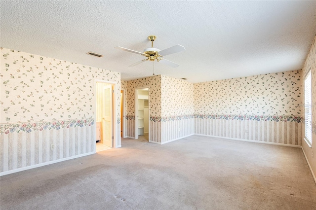 spare room featuring light carpet, ceiling fan, and a textured ceiling