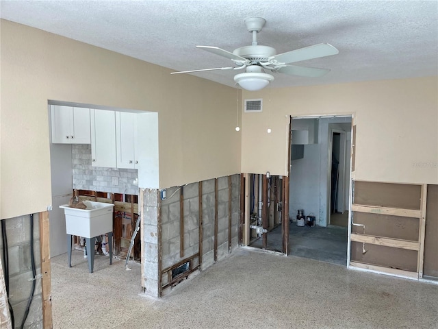 interior space with ceiling fan, sink, and a textured ceiling