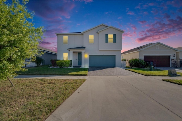 view of front of property with decorative driveway, a lawn, an attached garage, and stucco siding