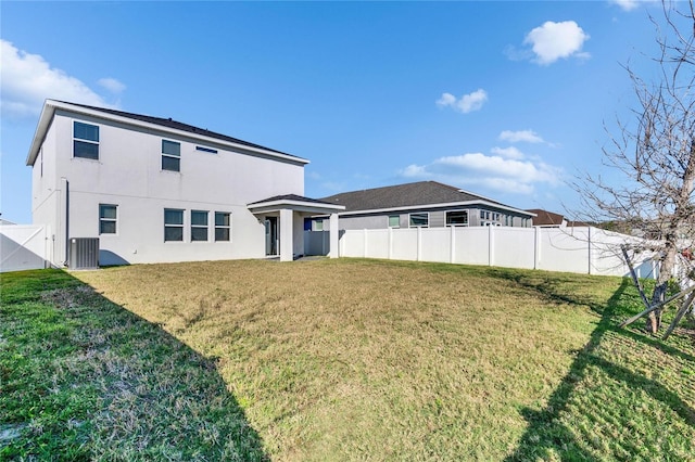 rear view of house with a lawn, fence, central AC, and stucco siding