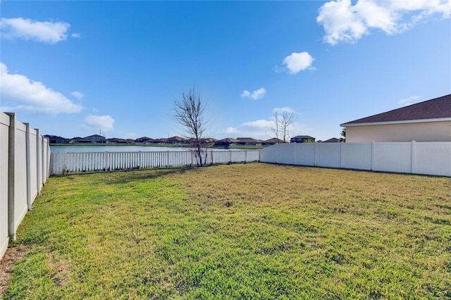 view of yard featuring a water view and a fenced backyard