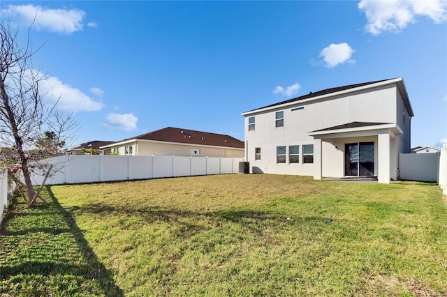 rear view of house with a fenced backyard, a yard, and stucco siding