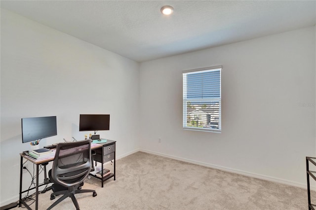 carpeted office space with a textured ceiling and baseboards