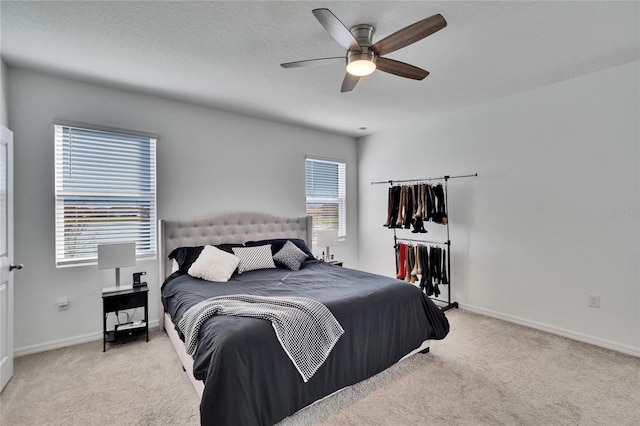 bedroom with baseboards, a textured ceiling, and light colored carpet