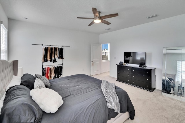 bedroom featuring light colored carpet, ceiling fan, visible vents, and multiple windows