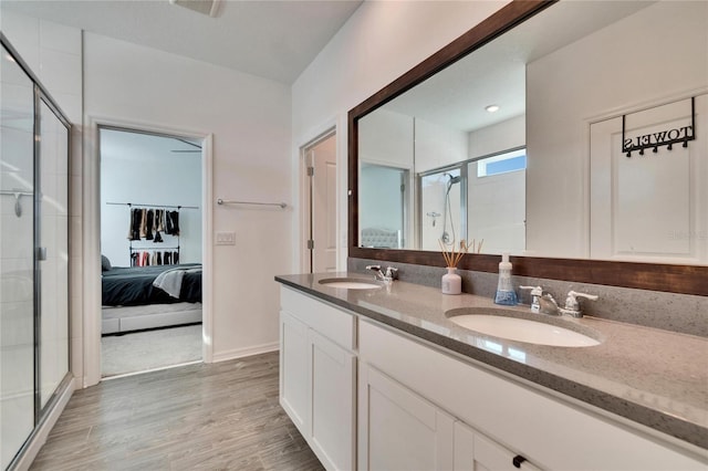 ensuite bathroom featuring a shower stall, wood finished floors, a sink, and ensuite bathroom