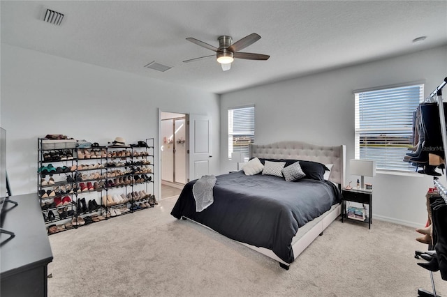 carpeted bedroom with multiple windows, connected bathroom, visible vents, and a ceiling fan