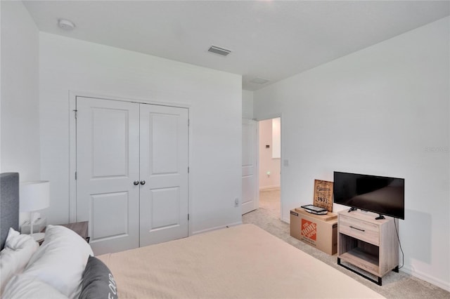 bedroom featuring a closet, visible vents, light carpet, and baseboards