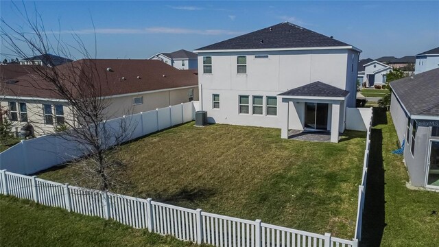 rear view of property featuring a residential view, a fenced backyard, a lawn, and stucco siding