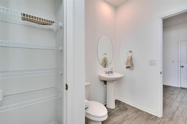 half bathroom with a sink, wood finished floors, toilet, and baseboards