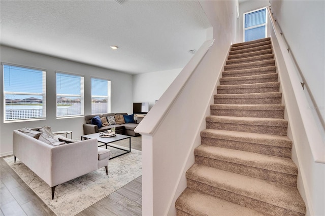 stairway featuring a textured ceiling and wood finished floors