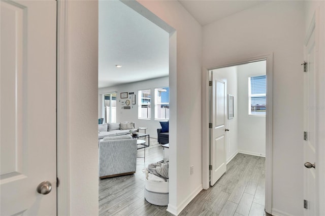 corridor featuring light wood finished floors and baseboards