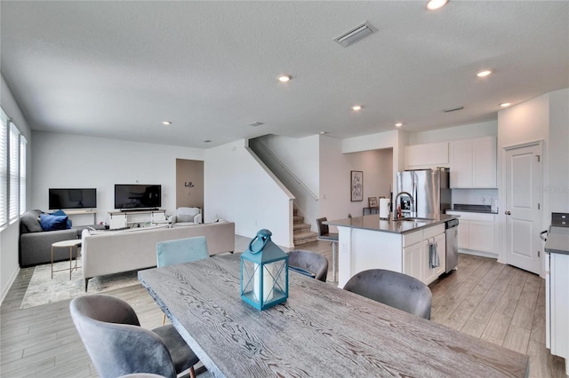 dining room with stairway, light wood-style flooring, visible vents, and recessed lighting