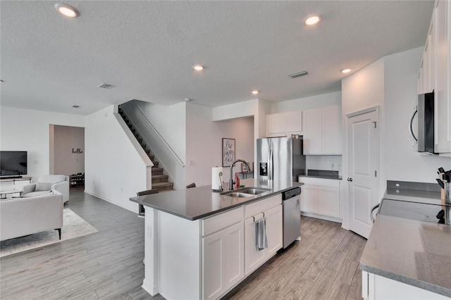 kitchen featuring stainless steel appliances, visible vents, light wood-style floors, open floor plan, and a sink