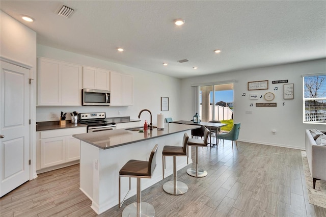 kitchen with appliances with stainless steel finishes, dark countertops, a sink, and visible vents